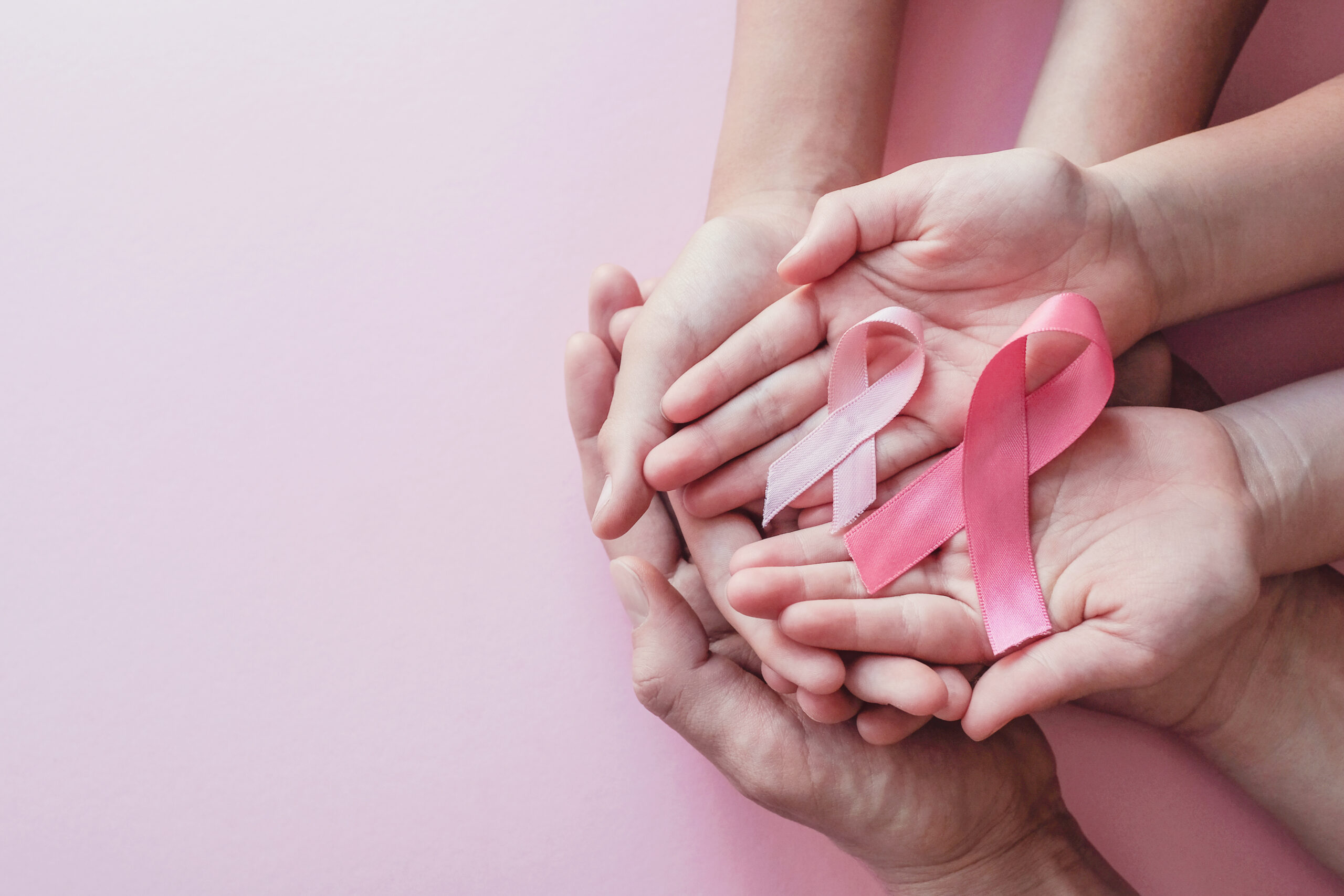 hands holding pink ribbons on pink background, Breast cancer awa